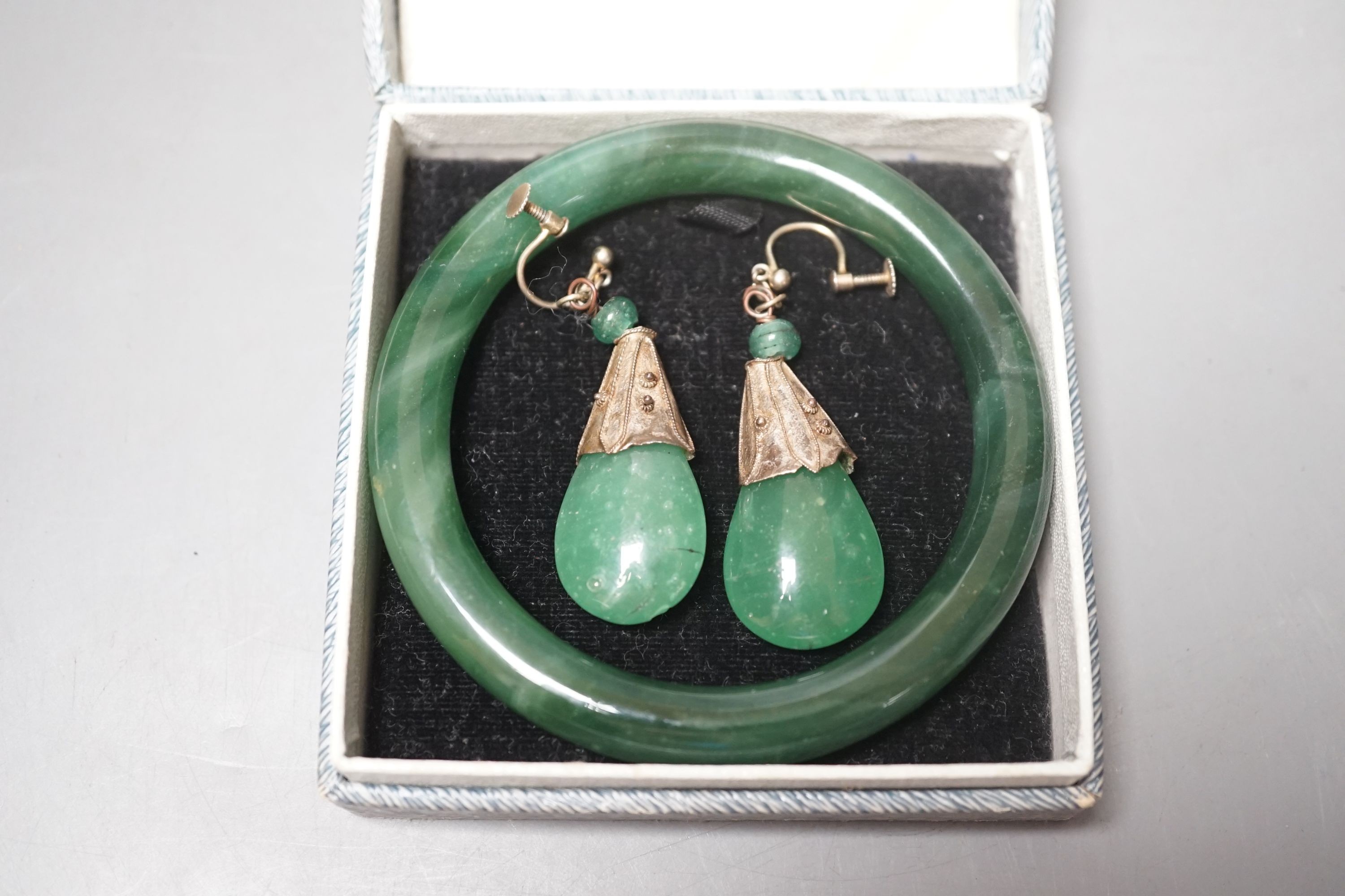 A Chinese carved bowenite jade pendant, a pair of green paste earrings and a green paste bangle.